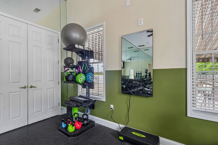Bright and inviting home gym corner featuring versatile workout equipment including kettlebells, resistance bands, and a sleek wall mirror.