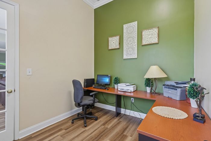 Charming home office with green accent wall, elegant desk setup, and warm lighting.