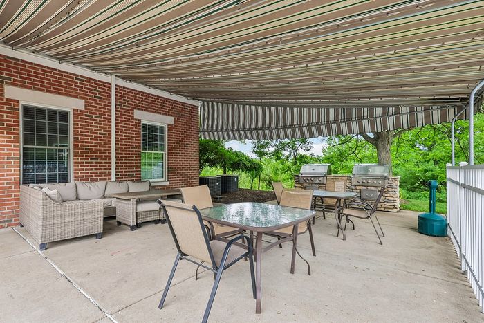Charming outdoor patio with comfortable seating, elegant shade canopy, and dual grills, perfect for entertaining and relaxation.