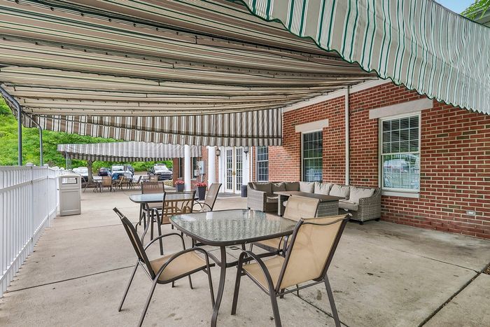 Charming patio with stylish striped awnings, brick wall, and cozy outdoor seating for relaxing gatherings.