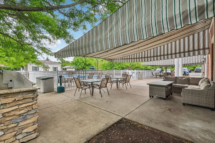 Inviting outdoor patio with stylish seating, a dining area under a chic striped awning, perfect for relaxation and entertaining.