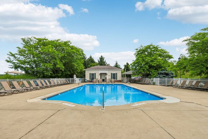 Inviting outdoor swimming pool surrounded by lush greenery and relaxing sun loungers, offering a serene escape.
