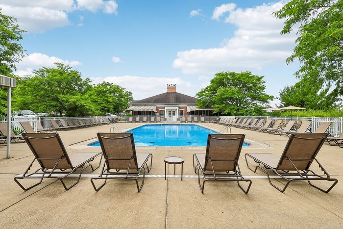 Inviting outdoor pool area with stylish lounge chairs and lush green surroundings, perfect for relaxation and leisure.