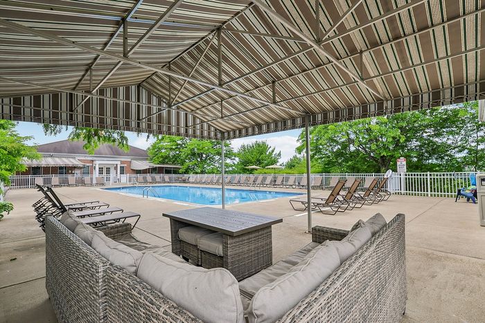 Inviting poolside lounge area with elegant seating under a stylish canopy, featuring a sparkling pool surrounded by sun loungers and lush greenery.