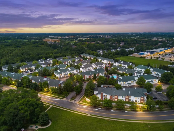 Scenic aerial view of a charming suburban neighborhood at sunset, showcasing elegant homes surrounded by lush greenery, inviting tranquility and comfort.
