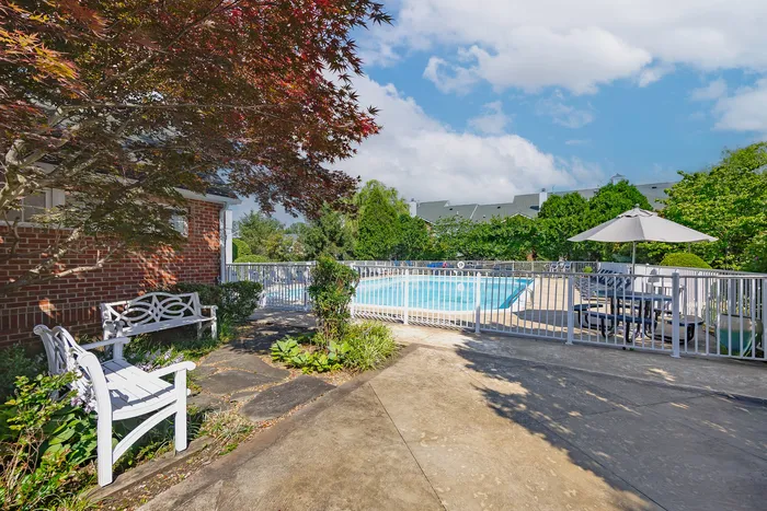 Inviting outdoor pool area with lush greenery and cozy benches, perfect for relaxation.