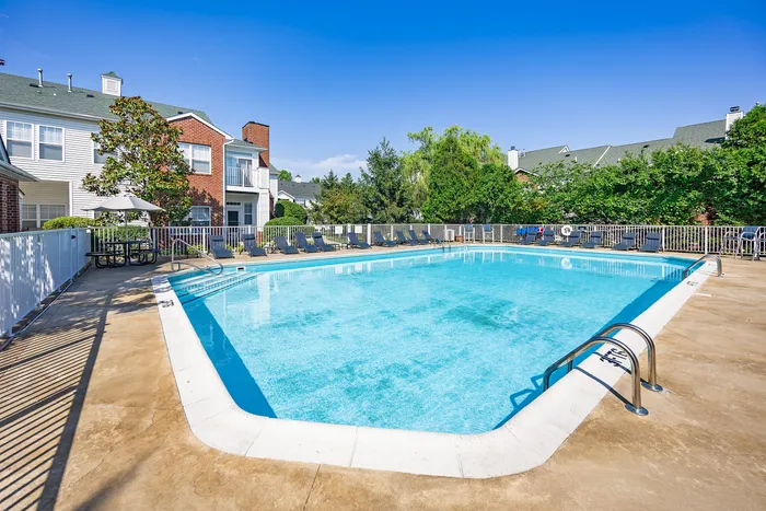 Inviting residential pool area surrounded by lush greenery and charming townhouses, perfect for relaxation and community gatherings.
