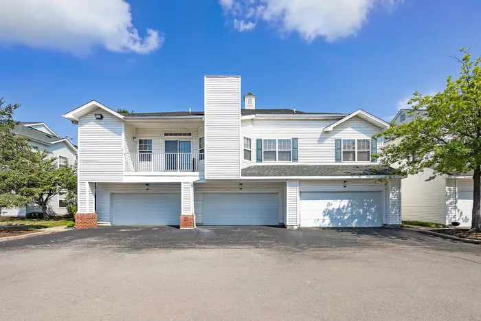 Charming townhouse with three-car garage and balcony set against a clear blue sky.