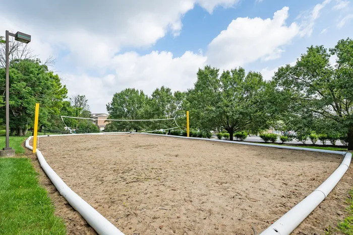 Inviting outdoor sand volleyball court surrounded by lush greenery and bright blue skies, perfect for recreational activities and enjoying nature.