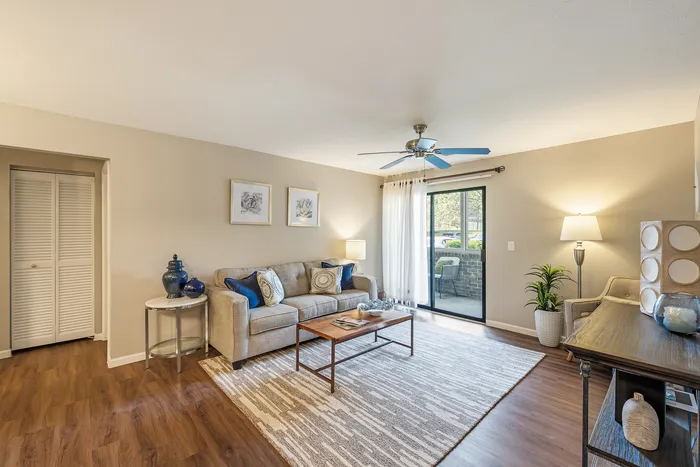 Bright and inviting living room with modern decor, featuring a plush sofa, stylish coffee table, and floor-to-ceiling window opening to a scenic balcony.