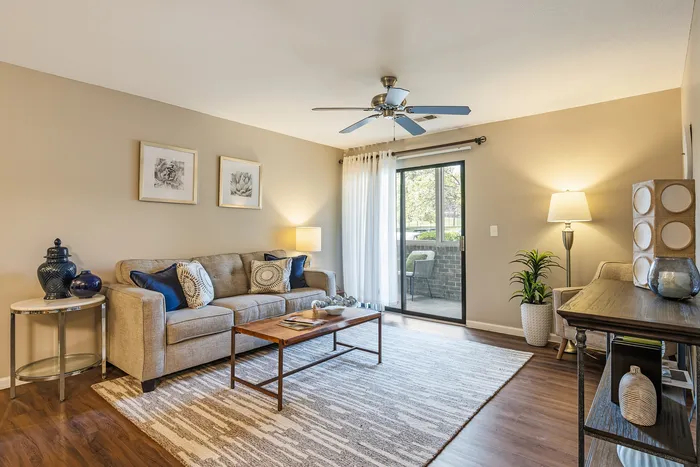 Bright and inviting living room with cozy seating, modern decor, and natural light streaming in through glass sliding doors.