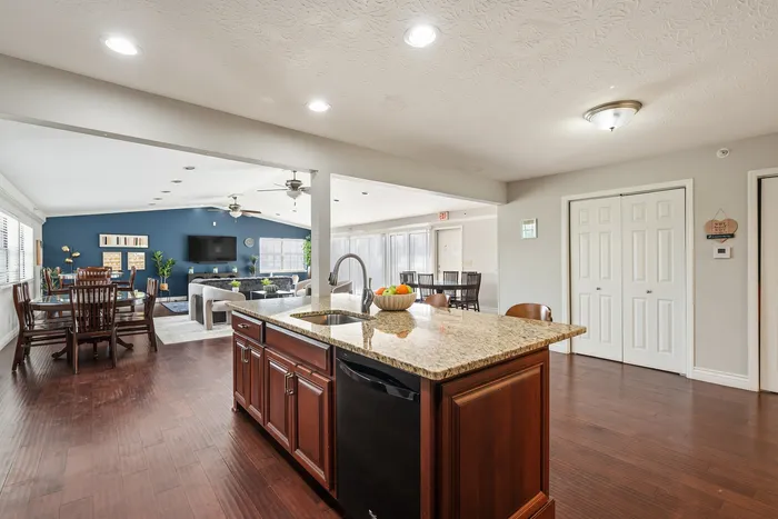 Elegant open-concept living space featuring a modern kitchen island, cozy dining area, and inviting living room with a stylish blue accent wall.