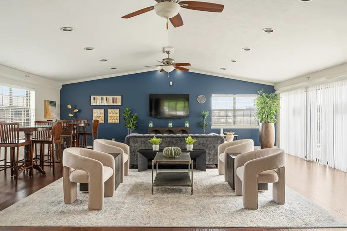 Elegant open-plan living room featuring plush seating, modern decor, stylish ceiling fans, and abundant natural light.
