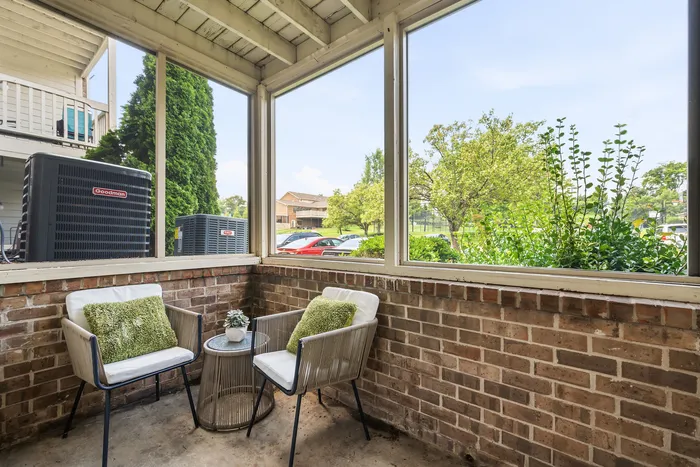 Charming enclosed patio with cozy seating and lush garden views, perfect for relaxation.