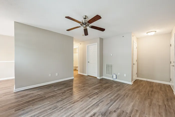 Inviting apartment interior with elegant wood flooring, neutral walls, and a stylish ceiling fan for a modern touch.