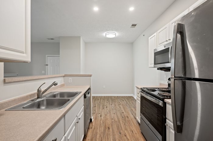 Modern kitchen with stainless steel appliances, sleek countertops, and stylish wood flooring offering a blend of function and style.