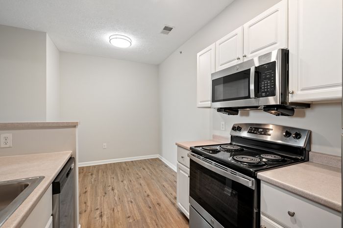Modern kitchen with sleek stainless steel appliances, elegant cabinetry, and chic wooden flooring.