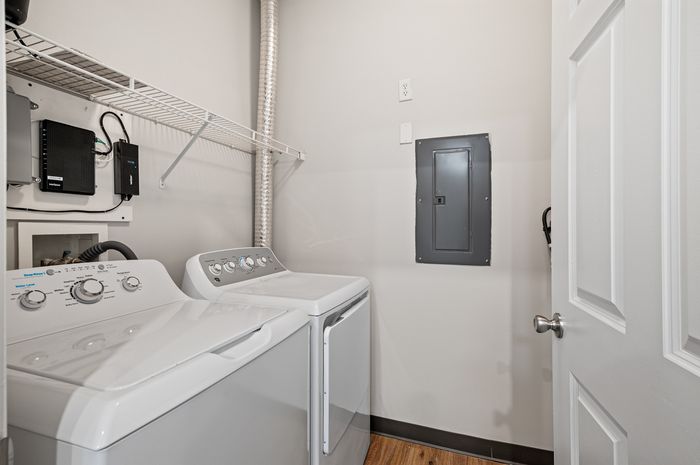 Modern laundry room featuring high-efficiency washer and dryer, sleek storage shelf, and easy access utility panel.