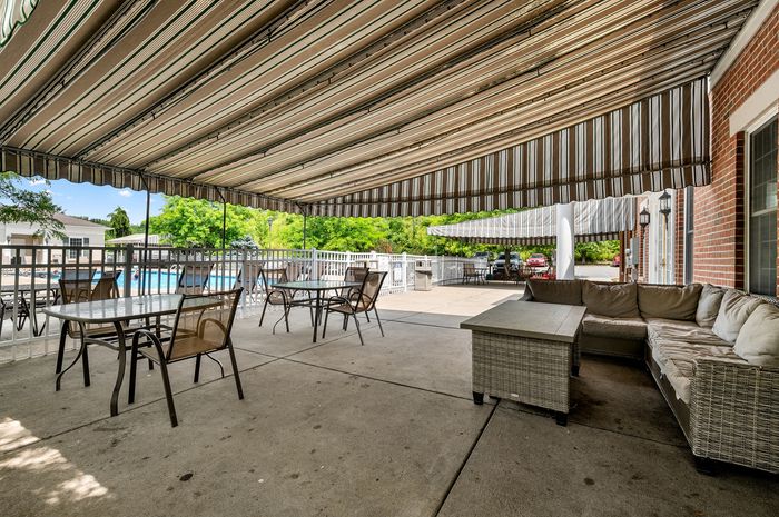 Inviting outdoor patio with stylish awning, cozy seating area, and poolside view, perfect for relaxation.