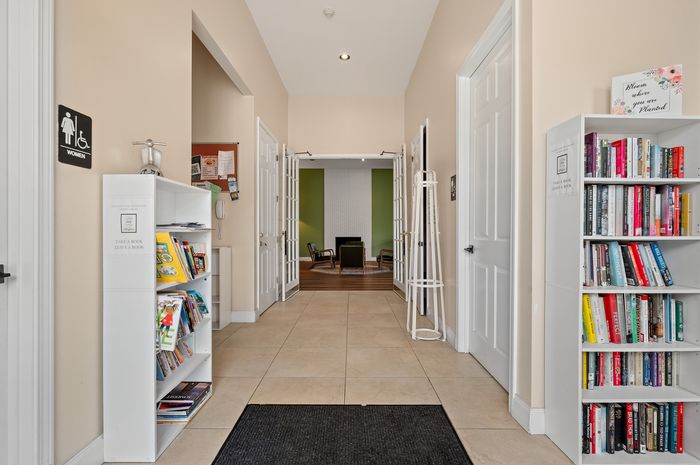 Inviting apartment hallway with elegant bookcases, contemporary decor, and cozy, well-lit seating area.