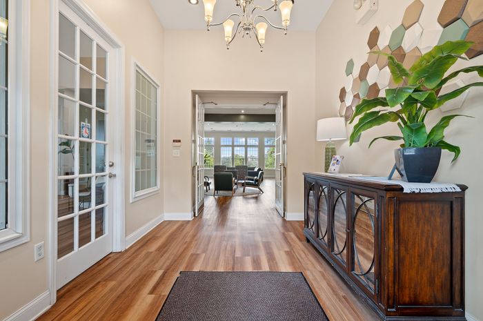 Elegant apartment entryway featuring stylish wood flooring, chic lighting, and a stunning view into a spacious living area.