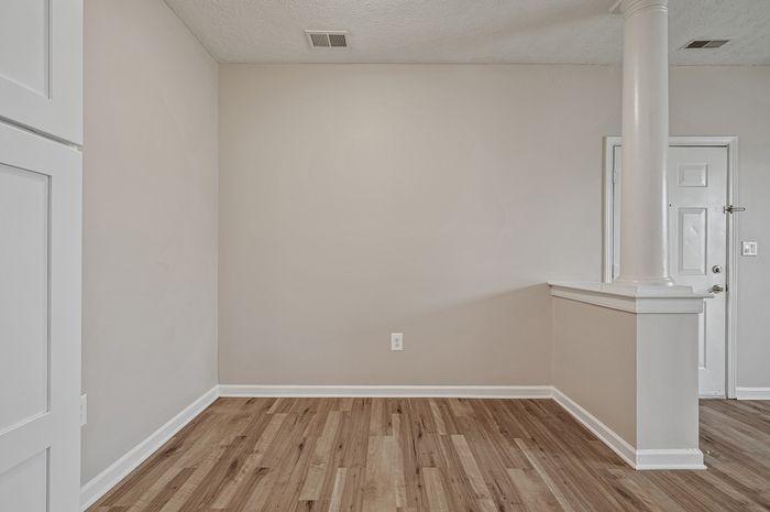 Bright and spacious room featuring elegant wooden flooring, modern column design, and freshly painted walls, perfect for a stylish living or dining area.