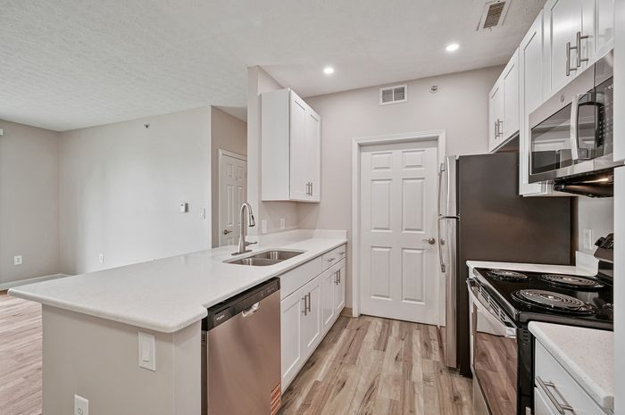 Modern kitchen with sleek white cabinetry, stainless steel appliances, and spacious countertops, perfect for culinary enthusiasts.