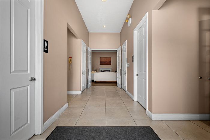Inviting hallway with soft beige walls, tiled flooring, and elegant double doors leading to a cozy lounge area.
