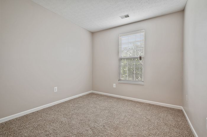 Bright and inviting room with plush carpeting and large window, perfect for a cozy retreat.