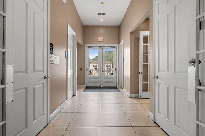 Inviting apartment entrance with polished tile floors, elegant white double doors, and abundant natural light, creating a welcoming atmosphere.