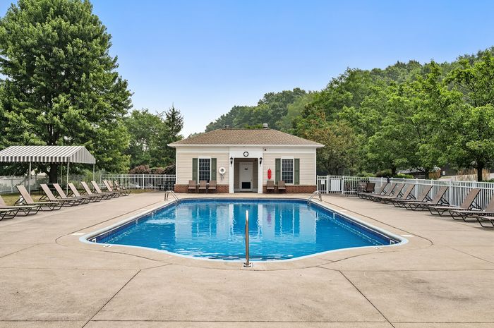 Inviting outdoor pool area with lush greenery, comfortable lounge chairs, and a charming pool house, perfect for relaxation and leisure.