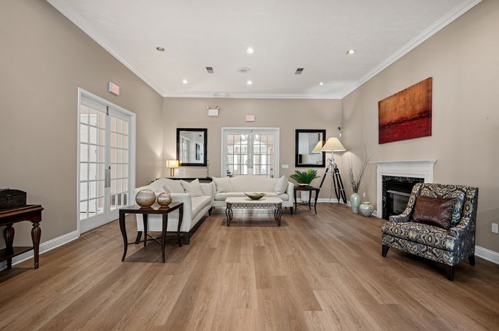 Elegant living room with contemporary decor, featuring cream sofas, a stylish armchair, and a cozy fireplace on sleek wooden flooring.