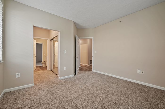 Inviting bedroom with plush carpet, ample natural light, and convenient access to a modern bathroom. Ideal for comfortable living.