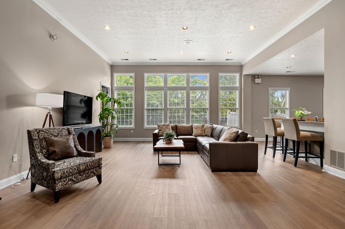 Elegant living room with floor-to-ceiling windows, stylish furniture, and open dining area perfect for entertaining.
