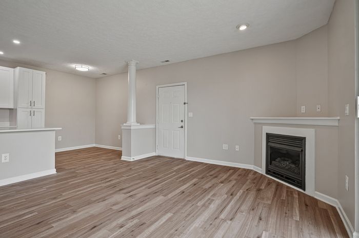 Modern open-concept living area with elegant hardwood floors, cozy fireplace, and sleek white cabinetry.