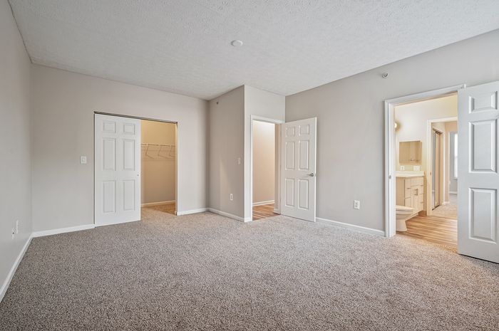 Spacious bedroom with plush carpeting, walk-in closet, and an en-suite bathroom boasting modern fixtures.