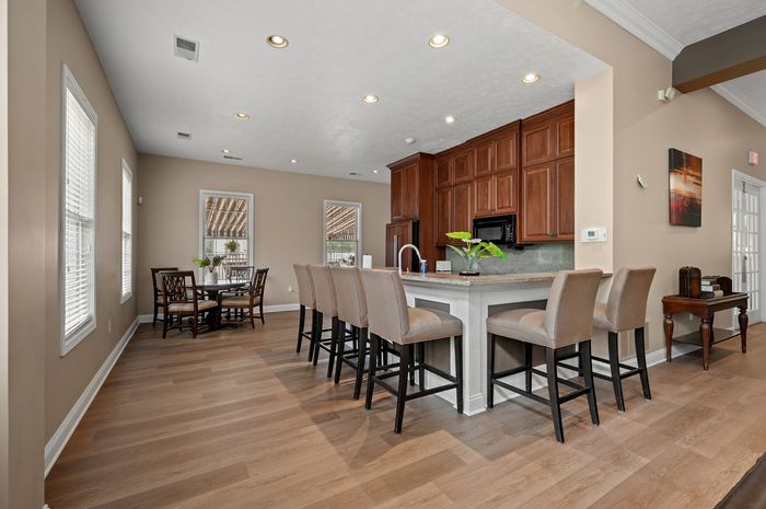 Elegant open-concept kitchen and dining area featuring warm wood cabinetry, modern bar seating, and abundant natural light.