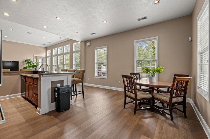 Bright and inviting open-plan kitchen and dining area with modern lighting, large windows, and elegant wooden flooring.