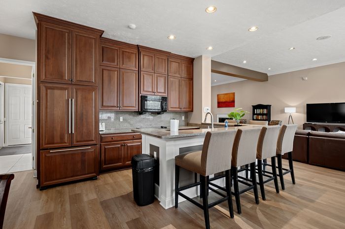 Chic open-concept kitchen with elegant wooden cabinetry, large island, and modern seating, flowing into a cozy living area.