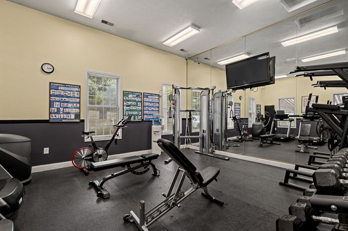 Modern fitness center featuring state-of-the-art exercise equipment, wall mirrors, and bright natural lighting for a revitalizing workout experience.