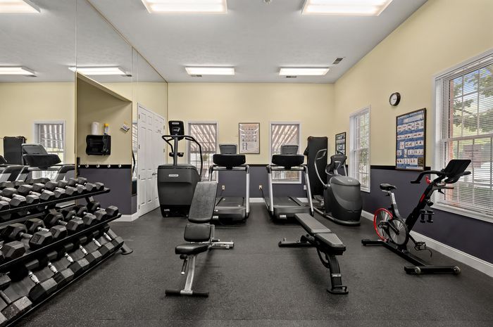 Modern fitness center featuring state-of-the-art exercise equipment, including treadmills, dumbbells, and stationary bikes, with ample natural light.