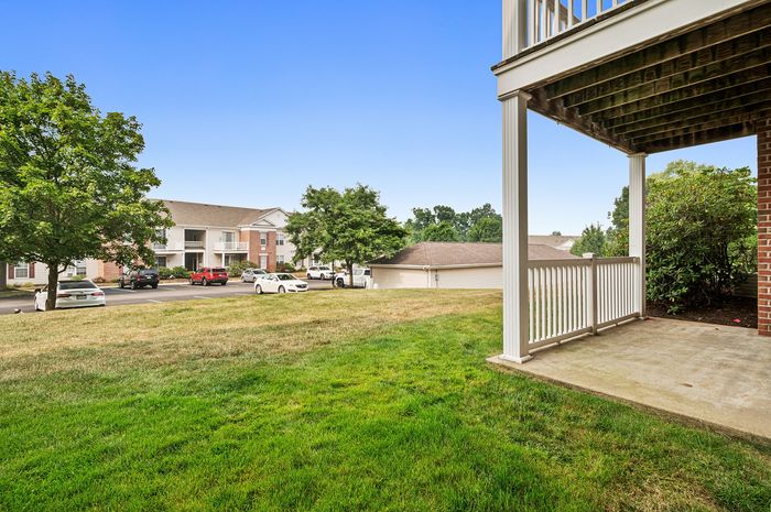Inviting apartment view showcasing lush green lawns, a spacious patio, and elegant exterior architecture in a tranquil neighborhood setting.