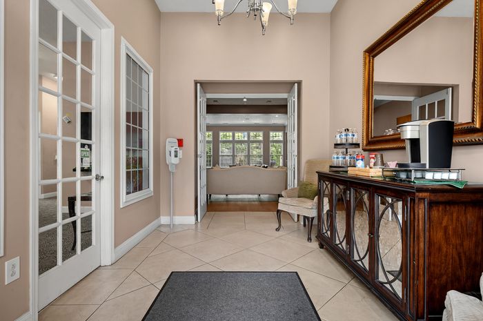 Inviting apartment foyer featuring elegant double doors, a cozy seating area, and a well-equipped refreshment station.