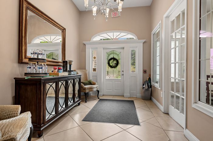 Inviting apartment entrance featuring elegant decor, a stylish mirror, and a cozy seating area with abundant natural light.