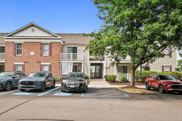 Charming brick-front apartment building with ample parking and lush greenery, offering a welcoming and serene living environment.
