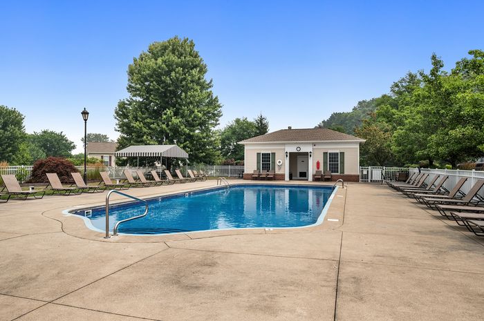 Inviting outdoor swimming pool with ample sun loungers surrounded by lush greenery, perfect for relaxation and leisure.