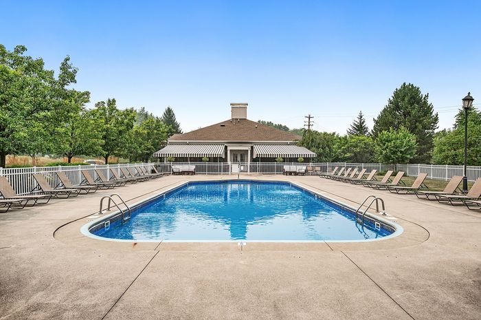 Inviting outdoor pool area with luxurious lounge chairs and lush green surroundings, perfect for relaxation and enjoyment.