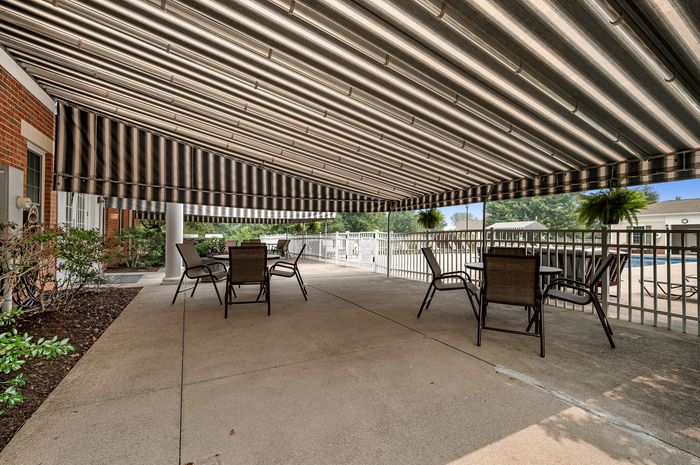 Elegant patio with striped awning, stylish outdoor furniture, and lush views, perfect for relaxation and entertainment.