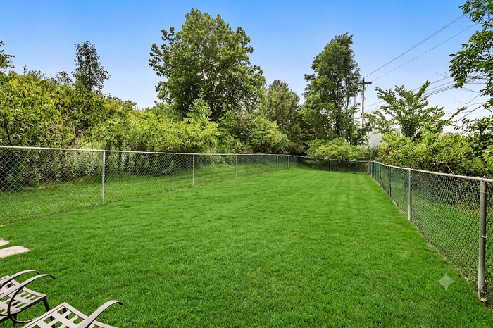 Expansive and lush fenced backyard with vibrant green lawn, ideal for recreation and relaxation.