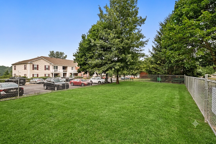 Charming residential building with spacious green lawn, surrounded by lush trees and convenient parking space.